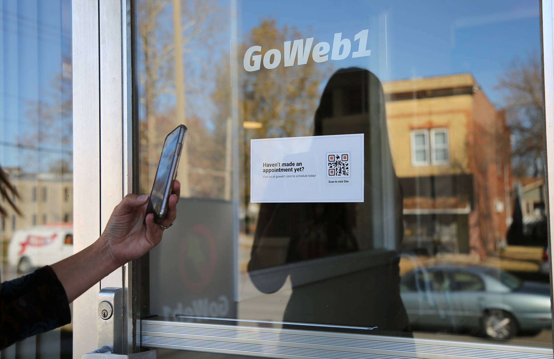 QR code displayed on a business storefront door for scheduling an appointment